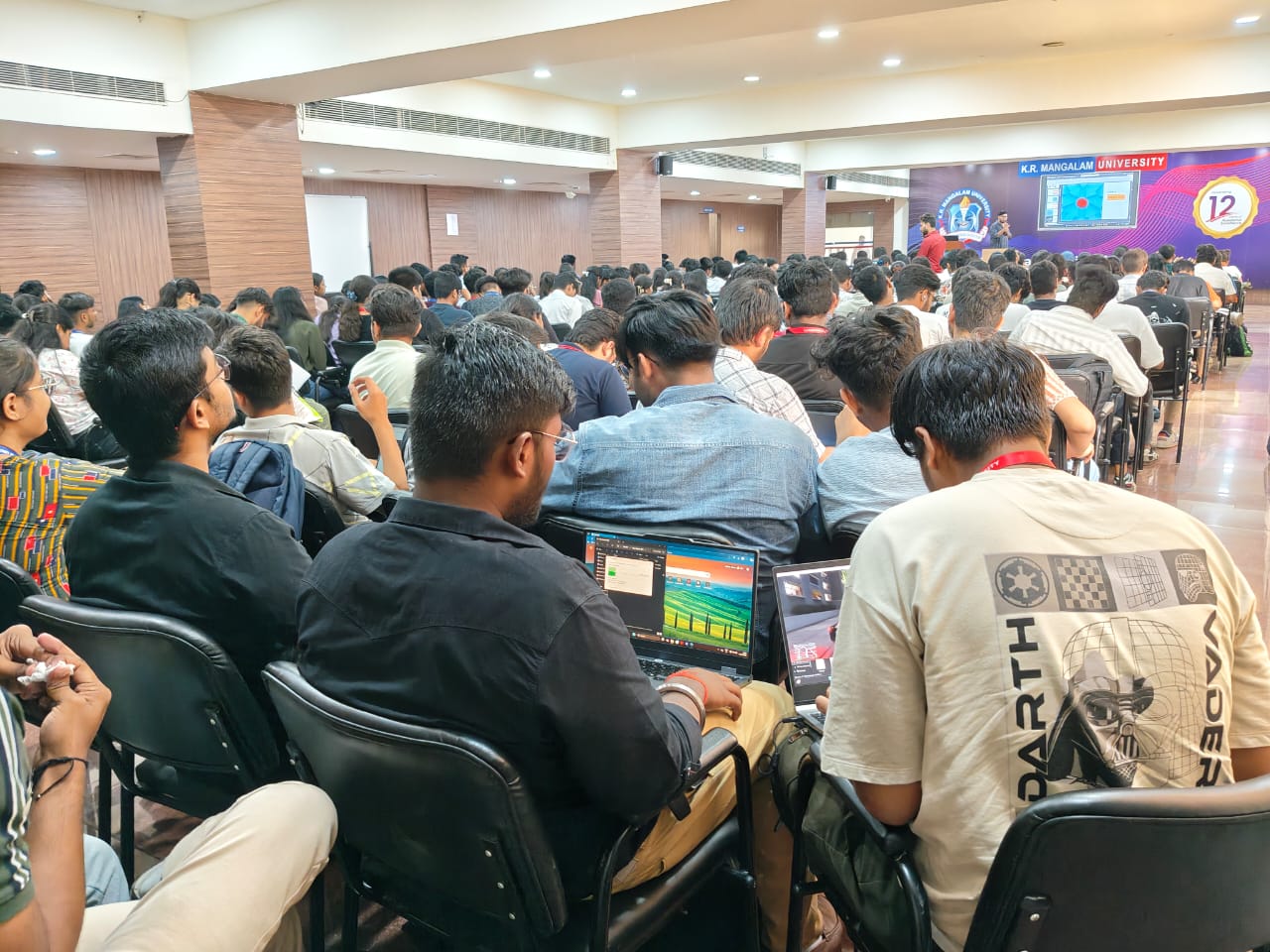 Rows of students with laptops filling a lecture hall at K.R. Mangalam University